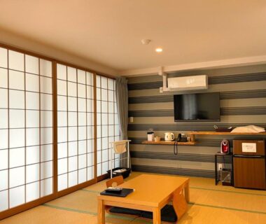 Tatami room with low table, shoji screens, wall-mounted TV and tea set at SEVEN SEAS HOTEL ITO Shizuoka