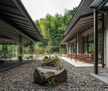 Gravel courtyard with moss-covered stones, glass corridors and wooden veranda seating at SOKI ATAMI in Shizuoka