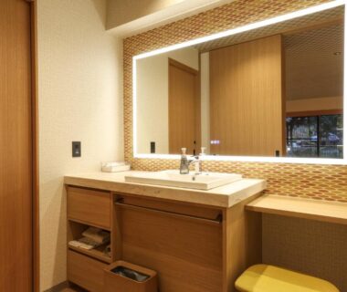 Illuminated bathroom vanity with wooden cabinetry, sink and stool at SPA TERRACE Shisui, Hyōgo, Kansai