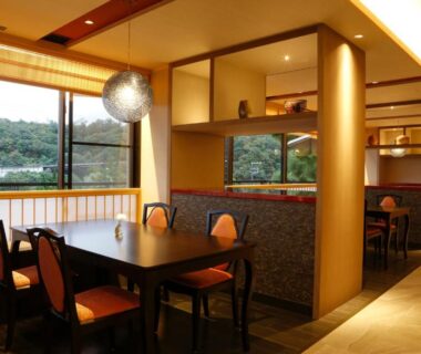 Dining area with wooden partitions, tables and chairs, large window with riverside view at SPA TERRACE Shisui, Hyōgo