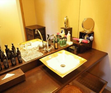 Sink and vanity with toiletries, mirror and woven stools at Sado Resort Hotel Azuma, Niigata