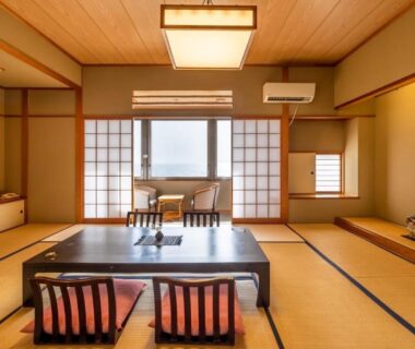 Traditional tatami room with low table, floor chairs, shoji screens and distant water view through sliding windows