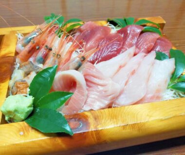 Wooden tray of assorted sashimi with shrimp, sliced fish, wasabi and leaves at Sado Ryosou Minato, Niigata