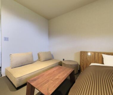 Bed, low wooden table and sofa cushions in a Saga Fuga guest room, Saga Kyushu