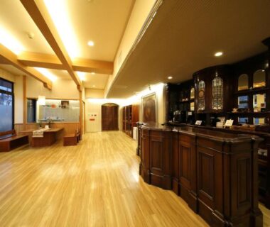 Warm reception area with wooden counter, polished hardwood floor and seating at Saga Grace Hotel, Kyoto
