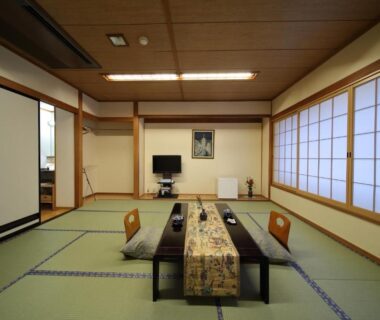 Traditional tatami room with low table, zabuton cushions, shoji screens and TV at Saga Grace Hotel, Kyoto