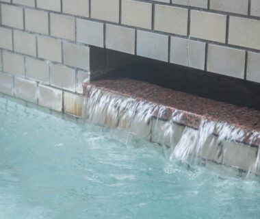 Tiled bath with flowing water from wall spout at Sagirisou in Nagano