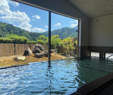 Indoor onsen with large window overlooking mountain garden at Sagirisou, Nagano