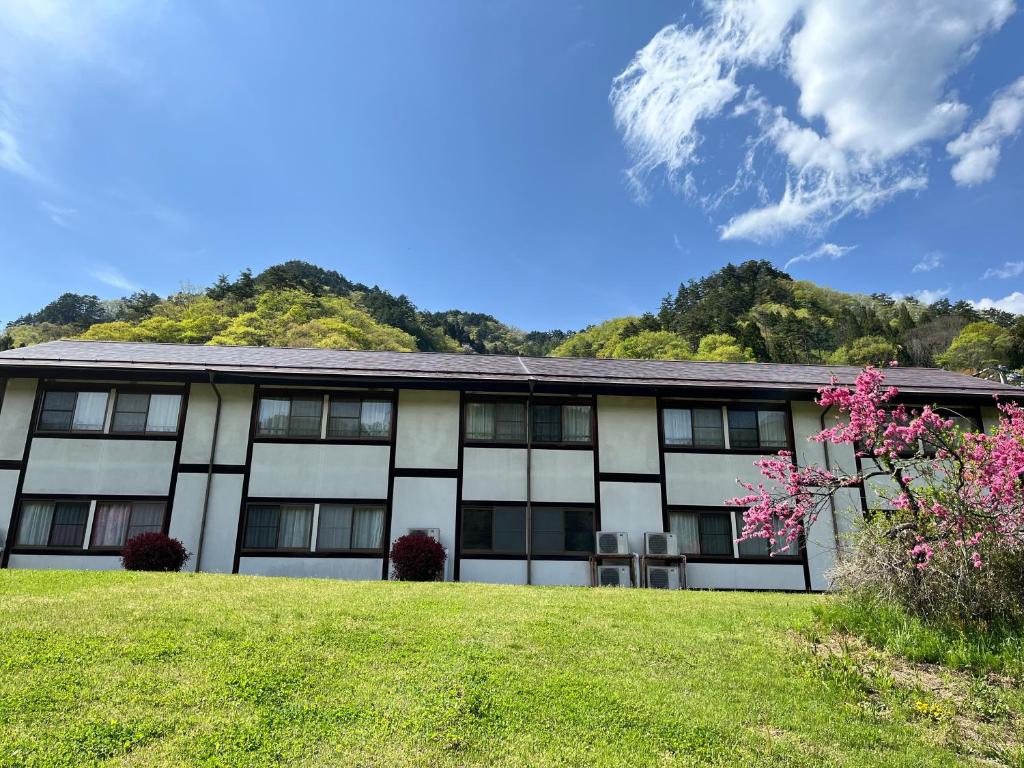 Ryokan exterior with lawn Sagirisou Nagano Low hillside view of Sagirisou ryokan facade, grassy lawn and flowering tree in Nagano, Chūbu region
