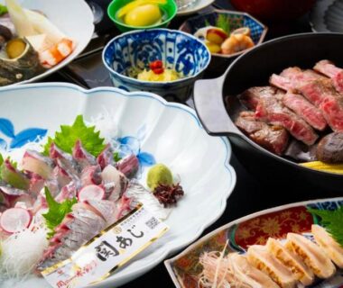 Assorted sashimi, grilled beef and side dishes arranged on table at Saigakukan in Ōita, Kyūshū, Japan