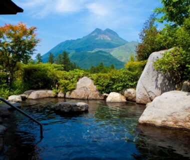 Stone-bordered outdoor onsen bath with mountain backdrop at Saigakukan in Ōita, Kyūshū, Japan