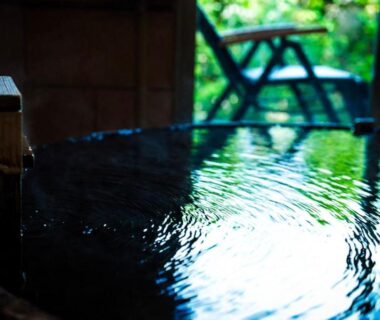 Rippling wooden onsen bath with garden view at Saigakukan, Oita