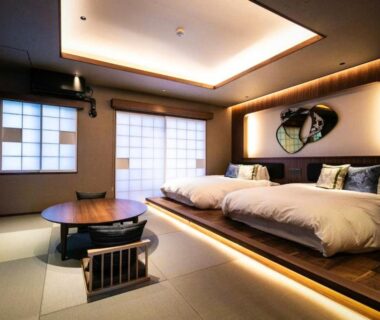 Raised wooden platform with twin beds, tatami flooring, shoji screens and low round table in elegant ryokan room