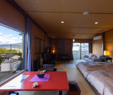 Spacious tatami room with low table, beds and large window facing mountains at Saikatei Jidaiya, Yamagata, Tōhoku, Japan
