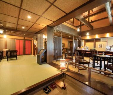 Traditional tatami lounge with low tables, wooden beams, lanterns and entrance step at Saikatei Jidaiya, Yamagata