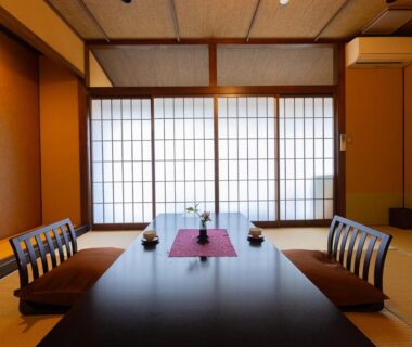 Traditional tatami room with low dining table, zabuton cushions and shoji screens at Saikatei Jidaiya in Yamagata