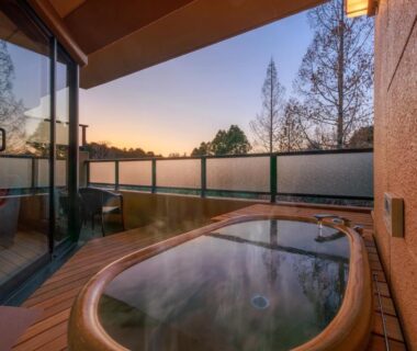 Outdoor wooden bath on room balcony overlooking treetops at sunset, Saiou no Miya, Mie