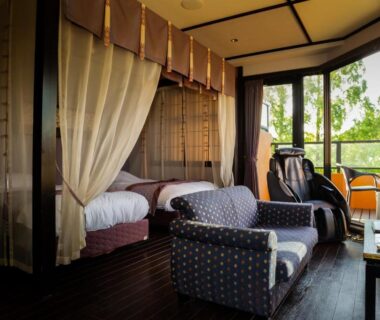 Canopy twin beds, armchairs and massage chair by balcony overlooking greenery at Saiou no Miya, Mie, Kansai