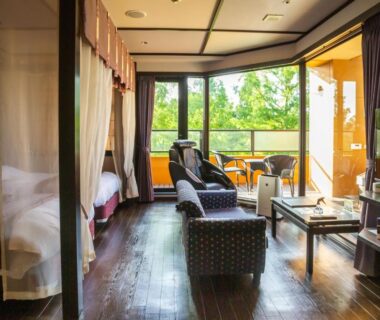 Spacious room with twin beds, seating area, TV and balcony overlooking lush greenery at Saiou no Miya Mie