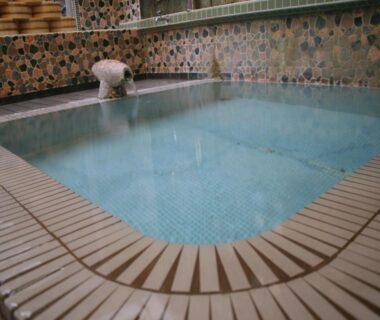 Tiled indoor onsen bath with mosaic walls and water spout at Sakaenoyu Ryokan in Nagano