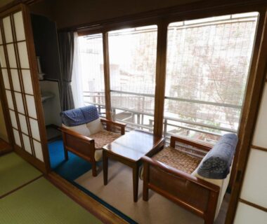 Tatami room corner with low table, wooden chairs, shoji screens and balcony view at Sakaenoyu Ryokan in Nagano