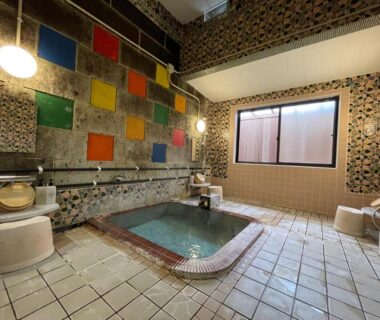 Indoor communal onsen with colorful mosaic tiles, washing stations and tiled floor at Sakaenoyu Ryokan Nagano