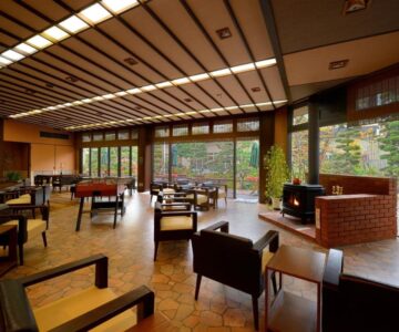 Lounge seating with fireplace and large windows overlooking garden at Sakaeya Hotel Yamagata