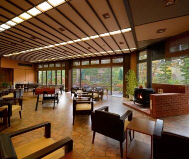 Lounge seating with fireplace and large windows overlooking garden at Sakaeya Hotel Yamagata