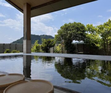 Wooden stools beside onsen bath overlooking trees and hills at Sakaeya Hotel Yamagata