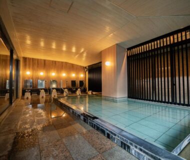 Tiled indoor onsen bath with wooden screens and warm lighting at Sakahijiri Nikko in Tochigi
