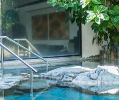 Rock-bordered onsen bath with metal handrail at Sakahijiri gyokushoen in Shizuoka, Chūbu