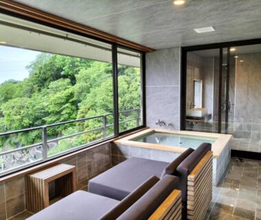 Tiled indoor soaking tub and lounge chairs facing forest view at Sakahijiri Gyokushoen in Shizuoka