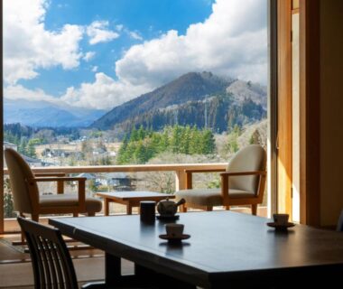 Low wooden table and chairs on tatami, shoji doors open to mountain view at Sakan Miyagi Tōhoku