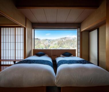 Twin futon beds in tatami room with shoji screens and distant mountain view at Sakan, Miyagi Tohoku