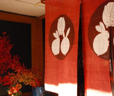 Red noren and floral arrangement at Sakaya Ryokan Yoshina Onsen in Shizuoka, Chūbu, Japan