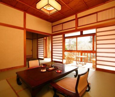 Traditional tatami room with low wooden table, zabuton chairs, shoji screens and outside view at Sakaya Ryokan Yoshina Onsen, Shizuoka