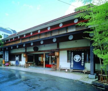Two-story wooden ryokan facade with noren curtains and bamboo at Sakaya Ryokan Yoshina Onsen Shizuoka