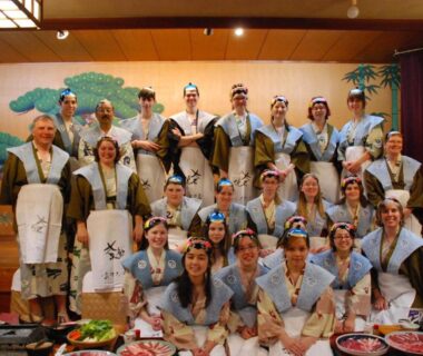 Guests and staff in traditional attire on a ryokan stage with banquet trays at Sakaya Ryokan Yoshina Onsen, Shizuoka