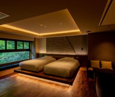 Low-lit modern Japanese room with twin beds, wooden flooring and large window at Sake Hotel Tamakiya, Niigata, Chūbu