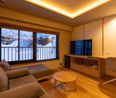 Cozy seating area with sofa, low wooden table and snowy window view at Sake Hotel Tamakiya, Niigata