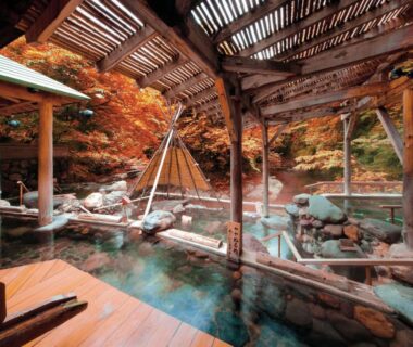 Steaming roofed wooden onsen bath with autumn maple foliage at Sakunami Onsen Yuzukushi Salon Ichinobo Miyagi