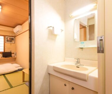 Tatami room with futon bedding and adjoining wash basin area at Sakura Ryokan Asakusa Iriya in Tokyo