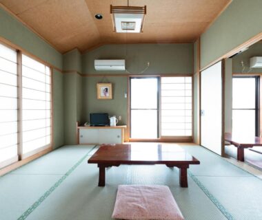 Bright tatami room with low wooden table, zabuton cushion, shoji screens and sliding doors at Sakura Ryokan in Tokyo