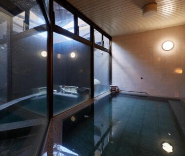 Indoor onsen bath with tiled pool and large windows at Sakura no Yakata Hotel, Yamanashi, Chubu