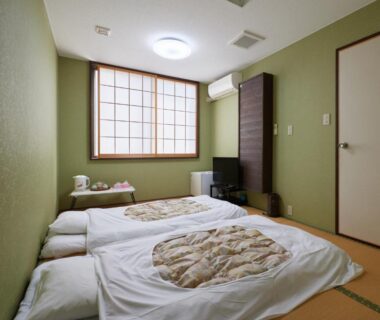 Traditional tatami room with futon bedding, shoji window, low table and tea set at Sakura no Yakata Hotel in Yamanashi