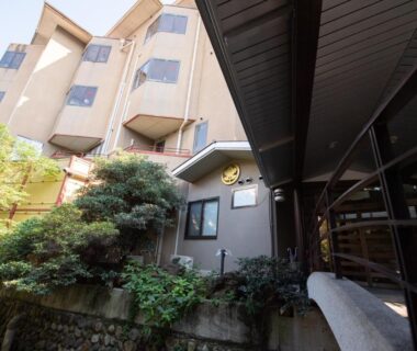 Exterior view of Sakura no Yakata Hotel entrance with covered walkway and surrounding greenery in Yamanashi