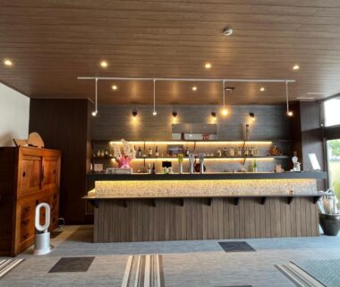 Ryokan reception with wooden counter, pendant lights, decorative shelving and seating at Sakuraya in Hiroshima