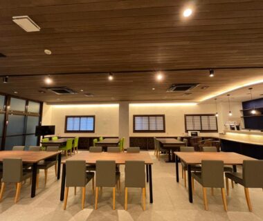 Spacious ryokan dining area with wooden ceiling, tables and chairs, counter seating and shoji-style windows at Sakuraya in Hiroshima