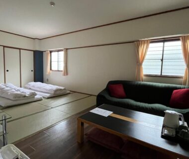 Spacious tatami room with folded futons, low table, green sofa with red cushions, sliding closet doors, Sakuraya Hiroshima