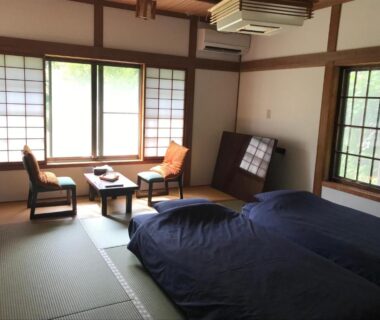 Traditional tatami room with futon bedding, low table, chairs and shoji screens at Samurai Hotel Naraiso in Nagano